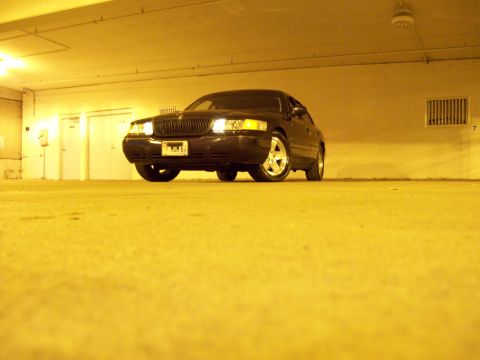 1999 Mercury Grand Marquis - A dark-colored 1999 Mercury Grand Marquis is shown from the front in a dimly lit indoor space.