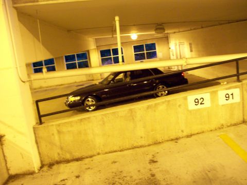 1999 Mercury Grand Marquis - A dark sedan is parked on a ramp in a parking garage, with visible damage to its front.