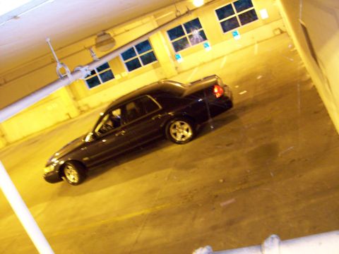 1999 Mercury Grand Marquis - A dark sedan is parked in an indoor space with yellow walls and multiple windows.