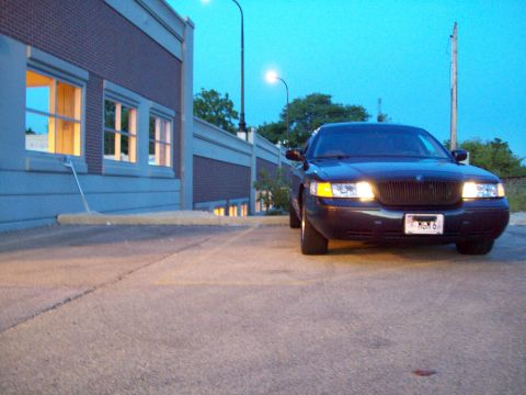 1999 Mercury Grand Marquis - A 1999 Mercury Grand Marquis is parked in front of a brick building at dusk.