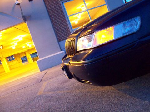1999 Mercury Grand Marquis - Dark sedan's front corner with grille and headlight illuminated in a parking garage.