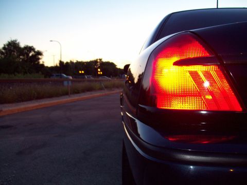 1999 Mercury Grand Marquis - The rear of a dark-colored vehicle is shown with its tail light illuminated against the twilight sky.