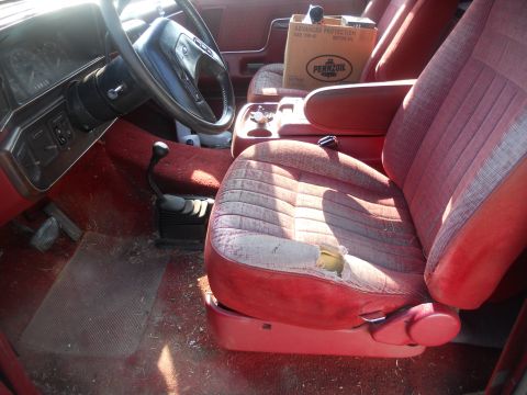 1991 Ford Bronco - The interior of this vehicle shows significant wear on the driver's seat and a box of oil on the passenger seat.