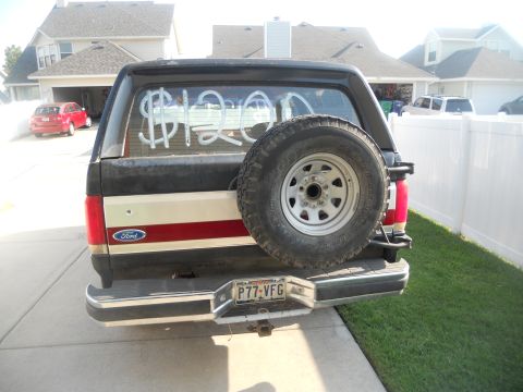 1991 Ford Bronco - Rear view of a 1991 Ford Bronco with graffiti on the rear window and a spare tire on the back.