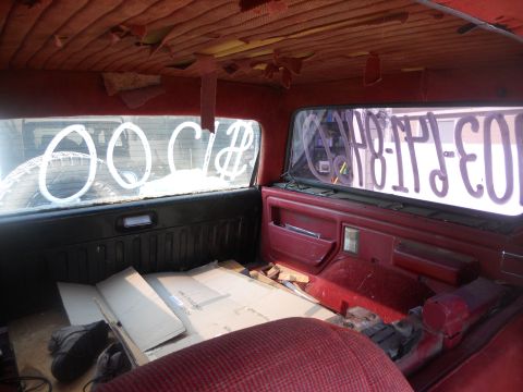 1991 Ford Bronco - The interior of a vehicle shows wear and tear, with writing on the rear window.