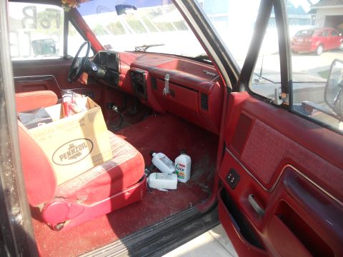 1991 Ford Bronco - The interior of a 1991 Ford Bronco shows red upholstery and a box of oil on the seat.
