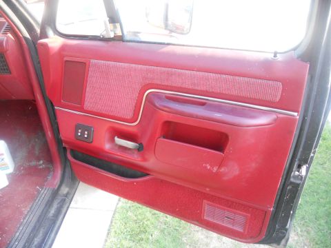 1991 Ford Bronco - Close-up of a red interior door panel, showing fabric inserts and storage compartments.