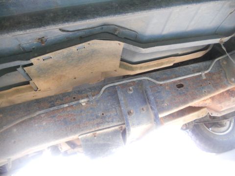 1991 Ford Bronco - Underside view of a vehicle's frame, fuel tank, and brake lines, showing signs of rust.