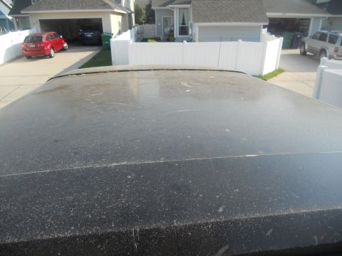 1991 Ford Bronco - View from above a dusty car roof, showing a suburban driveway with other vehicles and houses.
