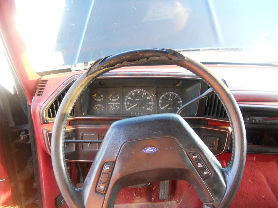 1991 Ford Bronco interior showing worn steering wheel, dashboard gauges, and Ford logo on steering wheel