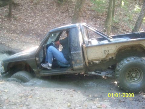 1989 Ford Bronco - A driver navigates a muddy trail in a heavily modified off-road truck.