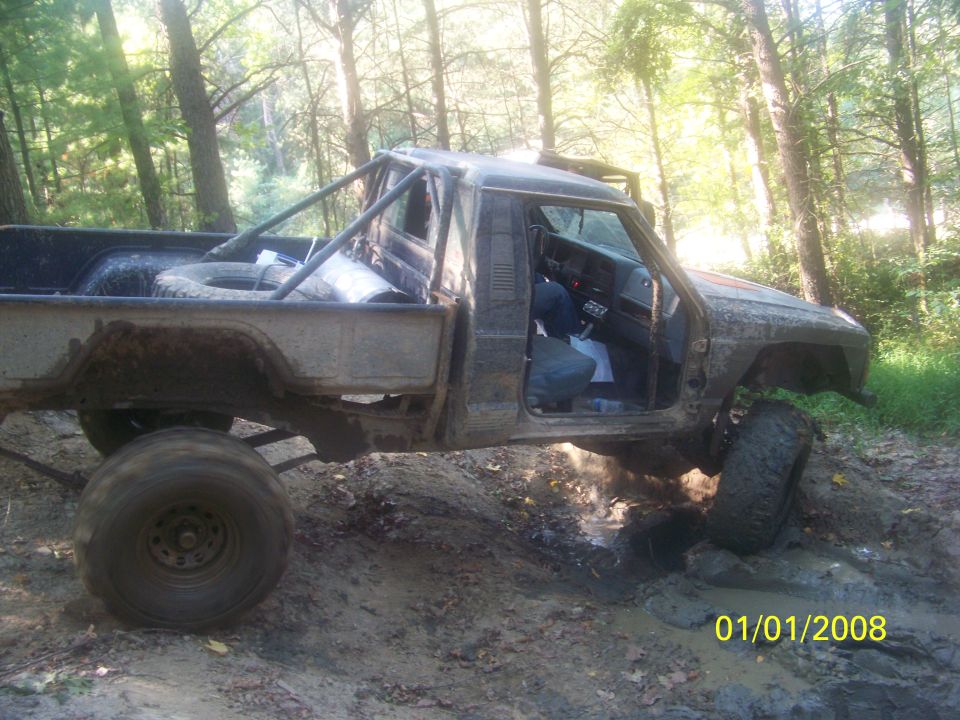 Modified pickup truck with roll cage stuck in mud on a trail