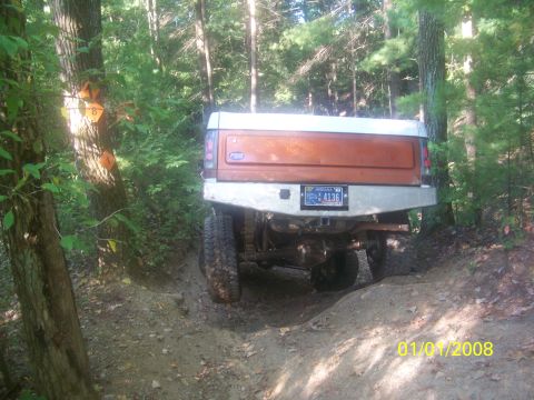 1989 Ford Bronco - 1989 Ford Bronco navigating a wooded trail with orange markers on trees.