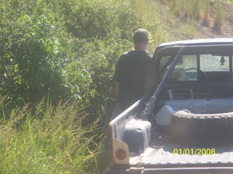 1989 Ford Bronco - A man stands next to the bed of a pickup truck, with a spare tire visible inside.
