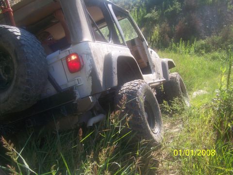 1989 Ford Bronco - This lifted off-road vehicle is seen on a grassy trail, likely during an off-road event.