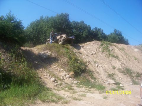 1989 Ford Bronco - A person stands by an off-road vehicle navigating a challenging dirt incline.
