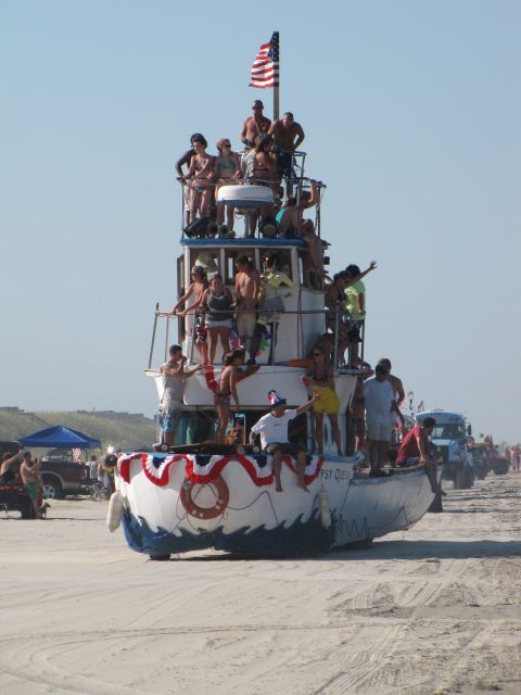 1979 Ford Bronco - A boat named Gypsy Queen is on the beach with people enjoying the day.