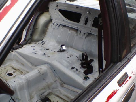 1994 Ford Crown Victoria - Interior view of a stripped-down vehicle with a roll cage and visible seatbelt.
