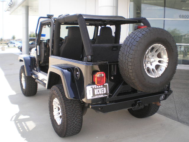 Black Jeep Wrangler rear view with spare tire and 'MCKED' license plate