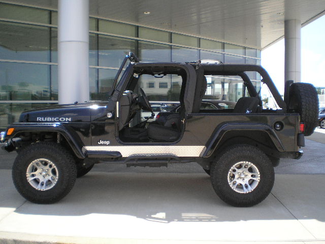 Black Jeep Wrangler Rubicon with silver trim on the doors, seen from the side
