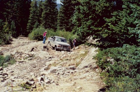 1995 Ford Bronco - A tan Ford F-Series truck attempts to traverse a difficult, rocky mountain path.