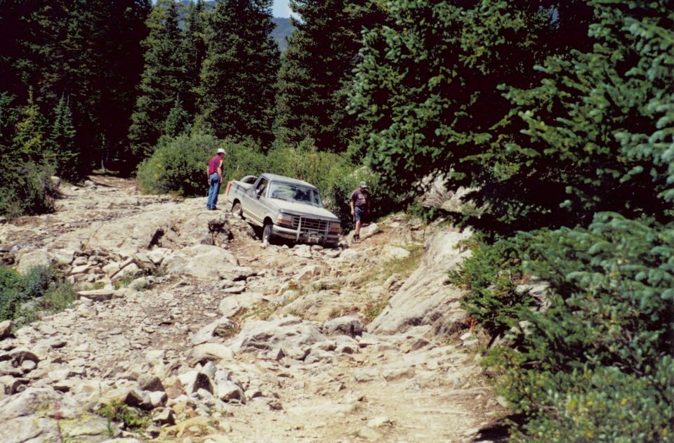 Tan Ford F-Series truck navigating a rocky, off-road trail