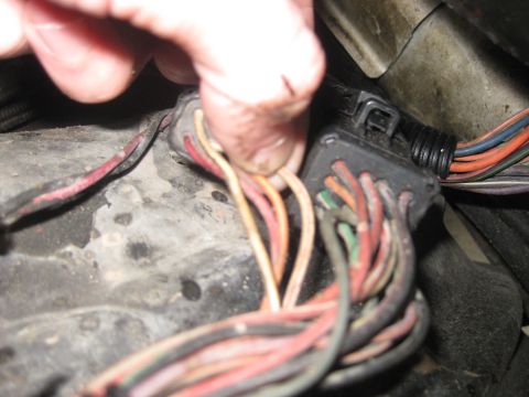 1994 Ford Bronco - A hand is shown connecting wires within a vehicle's complex electrical harness.