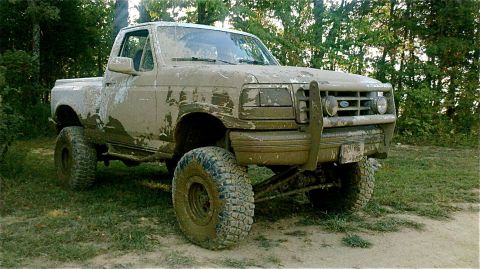 1995 Ford F-150 - This lifted pickup truck is covered in mud, suggesting it has been used off-road.