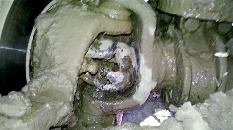 1995 Ford F-150 - Close-up of a heavily mud-covered vehicle suspension component, obscuring details.