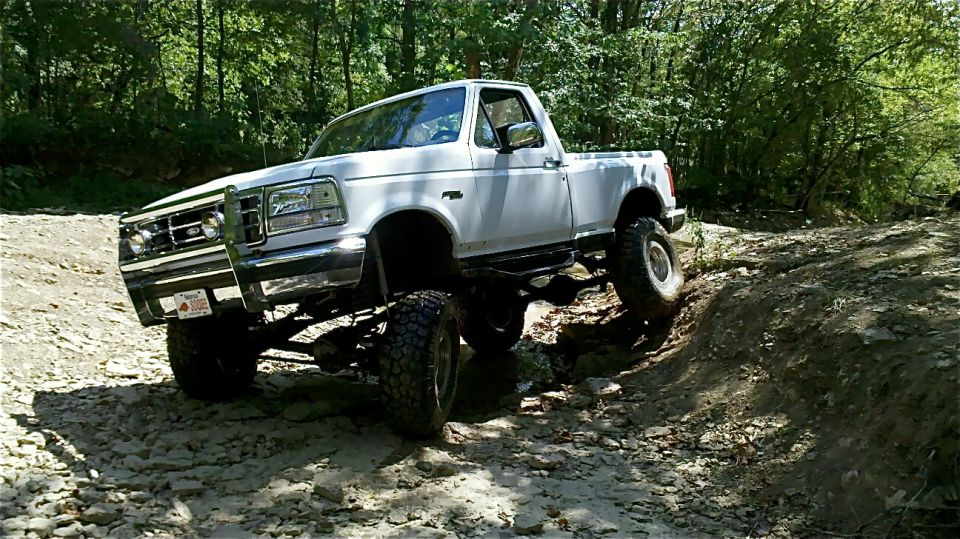 White 1995 Ford F-150 climbing a rocky incline off-road