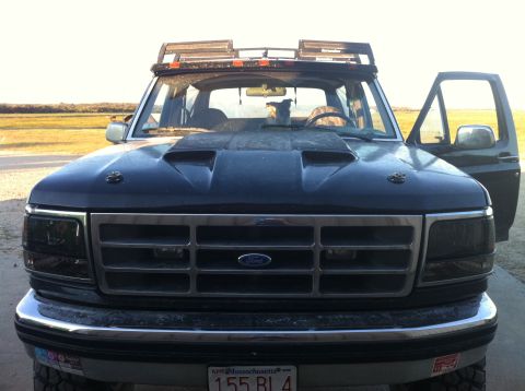 1993 Ford Bronco - Front view of a dark blue Ford truck with a hood scoop and a roof rack.