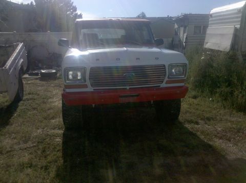 1979 Ford Bronco - Front view of a 1979 Ford Bronco with a red bumper and chrome grille. Another vehicle is partially visible.