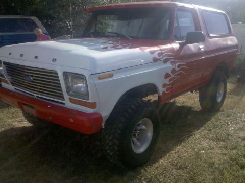 1979 Ford Bronco - This lifted Ford Bronco features a two-tone paint job with flame graphics and aggressive off-road tires.