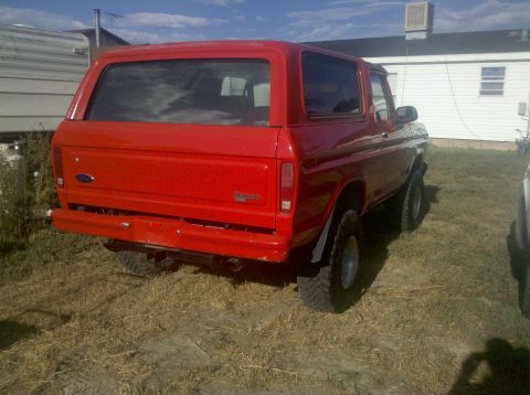 1979 Ford Bronco - Rear view of a red Ford Bronco with lifted suspension and off-road tires.