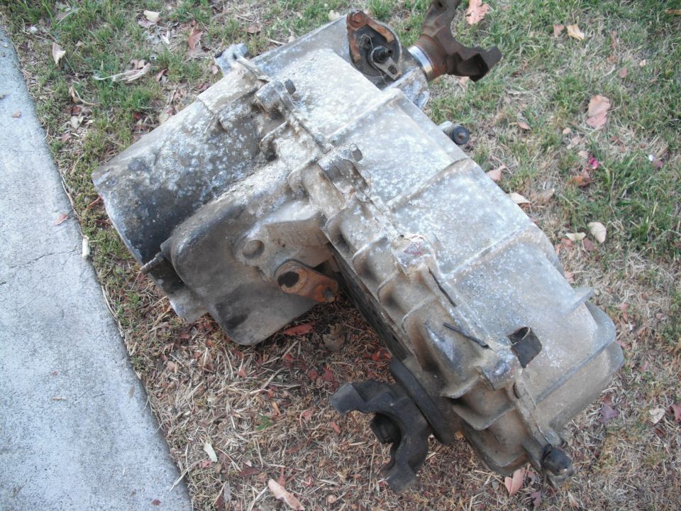 Transfer case with U-joints attached, resting on grass and dirt