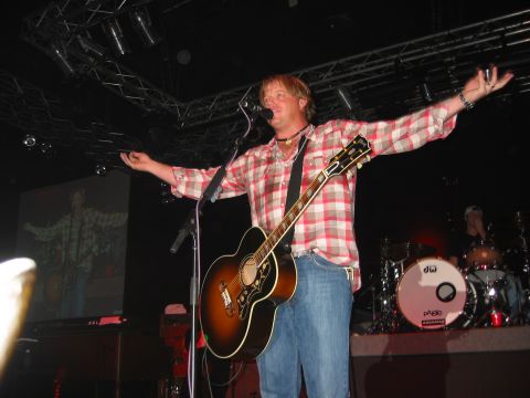 1989 Ford Bronco - A musician performs live on stage with his guitar and a drum kit visible.