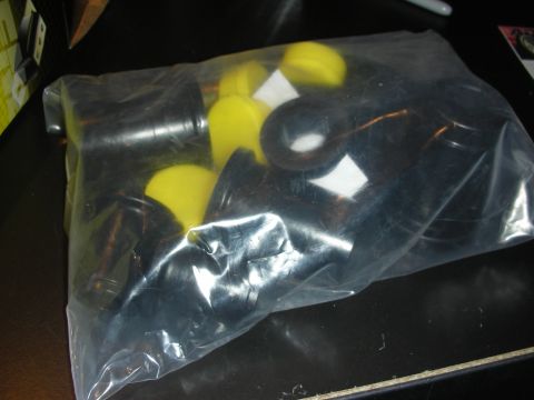 1998 Ford Crown Victoria - clear plastic bag holds an assortment of black and yellow polyurethane bushings with copper-colored metal sleeves.