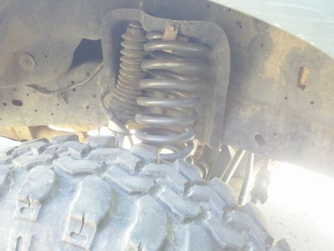 1989 Ford Bronco - This image shows the suspension system of a vehicle, focusing on the coil spring and part of the tire.
