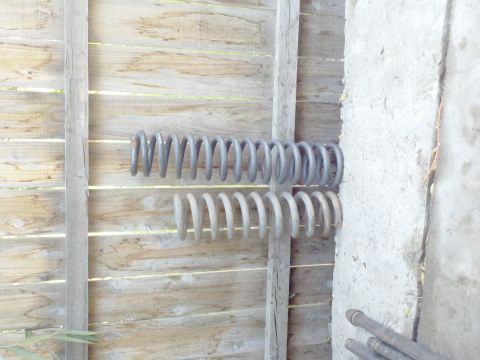 1989 Ford Bronco - Two suspension springs are mounted on a wooden fence, one above the other.