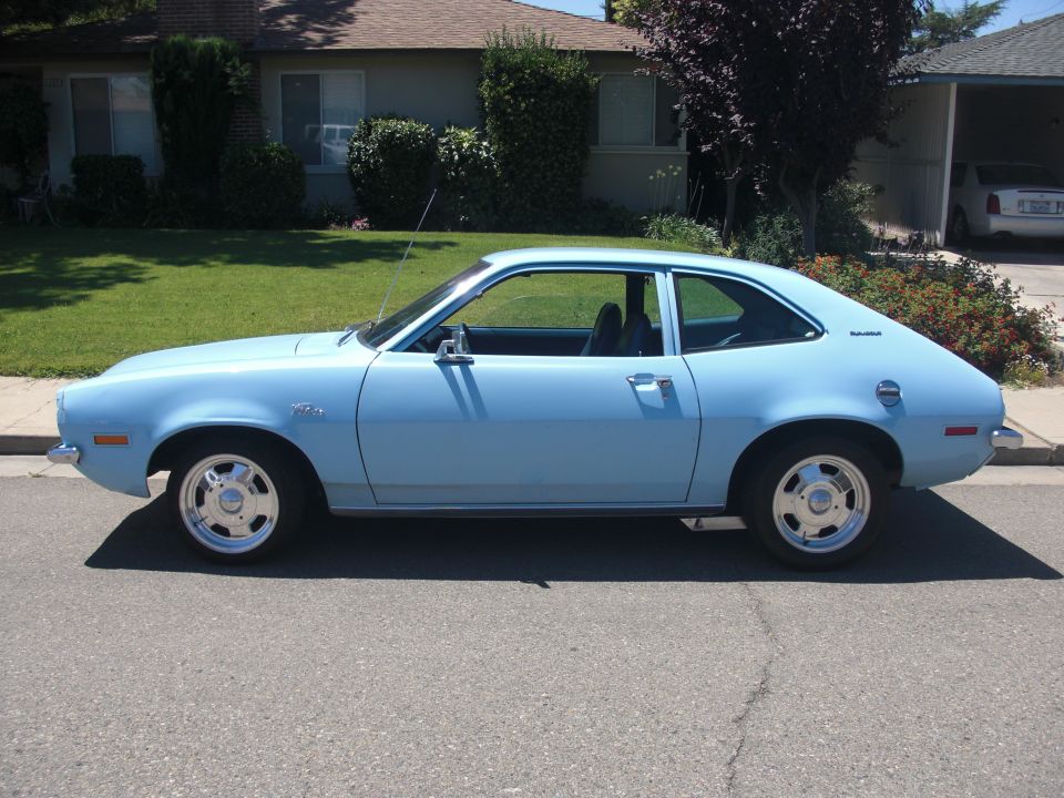 Light blue 1972 Ford Pinto coupe parked on a residential street, side view