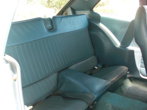 1972 Ford Pinto - The rear interior of a car shows blue vinyl seats and carpeting.