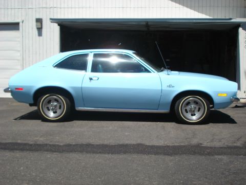 1972 Ford Pinto - A light blue 1972 Ford Pinto coupe is shown from the side, parked in front of a garage door.