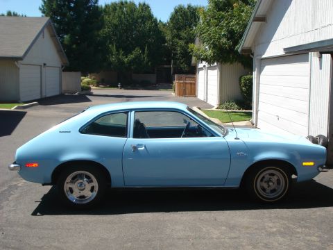 1972 Ford Pinto - Side view of a light blue 1970s coupe parked in a suburban driveway.