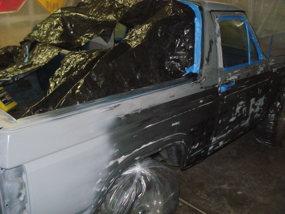 Truck body being prepped for paint, covered in primer and masking tape