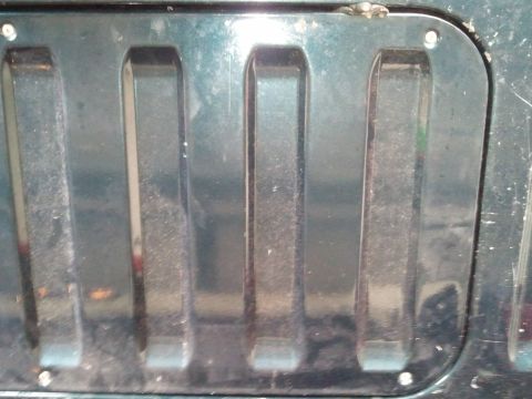 1994 Ford Bronco - A close view of the textured grille on a vehicle, showing its distinct vertical slots and metallic sheen.
