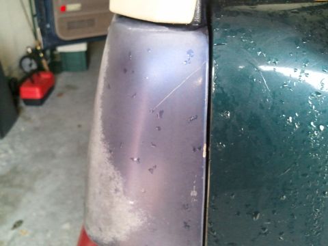 1994 Ford Bronco - Close-up of a vehicle's rear corner showing a purple tail light and green fender.