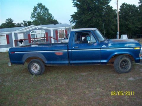 1979 Ford F-150 - A blue pickup truck is parked on a grassy area next to a mobile home.