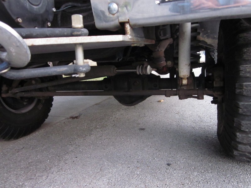 Undercarriage of a vehicle showing suspension and steering components, with large tires visible