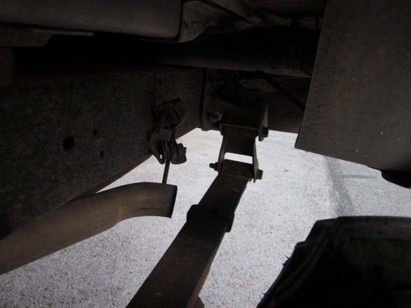 Undercarriage of a vehicle showing a leaf spring, exhaust pipe, and frame components. Visible text reads "SUPERMOTORS www.supermotors.net"