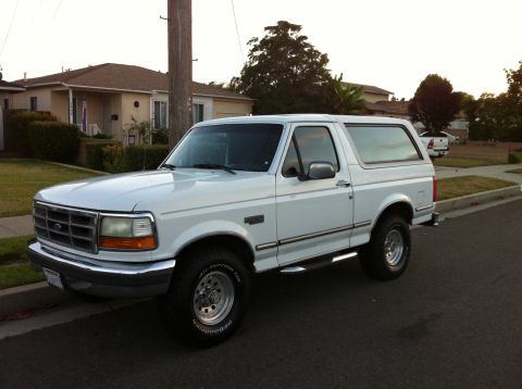 1992 Ford Bronco - This white 1992 Ford Bronco is parked on a suburban street, showing its classic SUV profile.